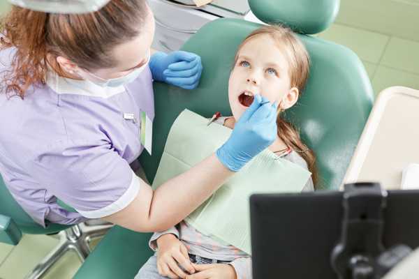 Little girl getting a fluride treatment from a dentist while sitting in a dental chair